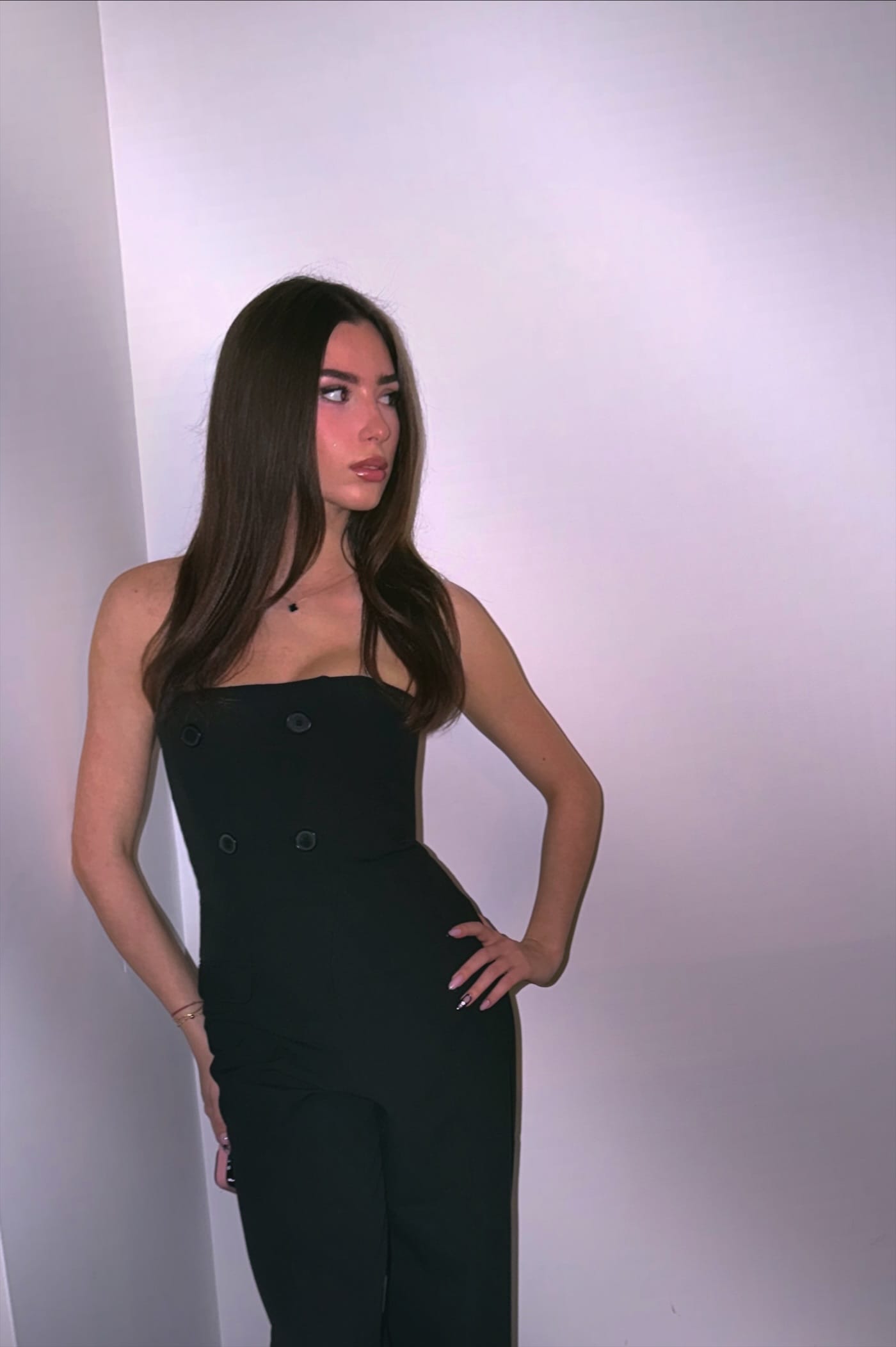 Ena Meleh in a black strapless jumpsuit, one hand on her hip