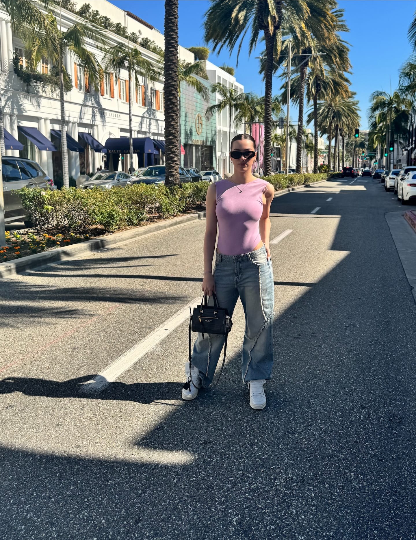 Ena standing on a sunny palm-lined street